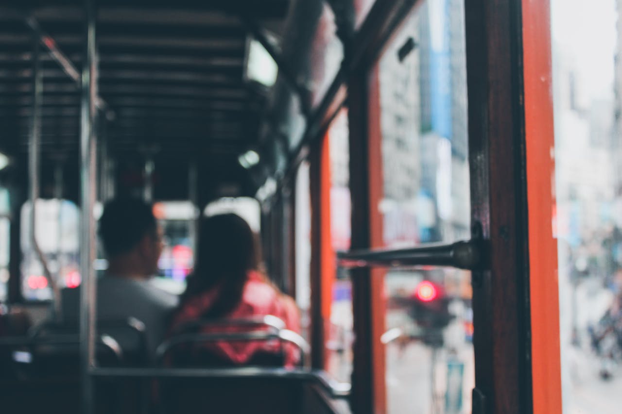 Blurred view inside a Hong Kong double-decker bus with commuters showing city life.